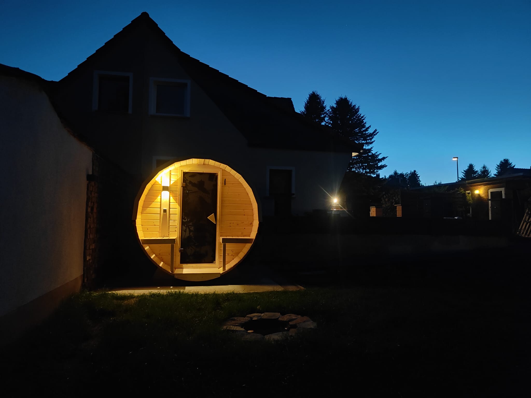 Fass-Sauna bei Nacht beleuchtet